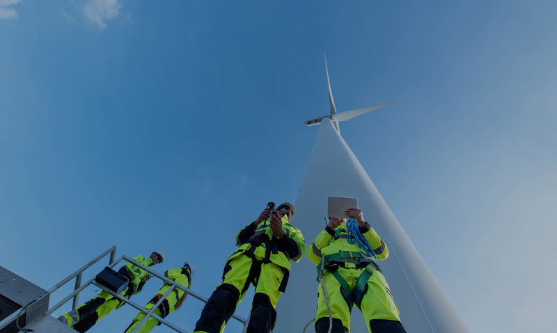 workers standing on the foot of a large windpower turbine